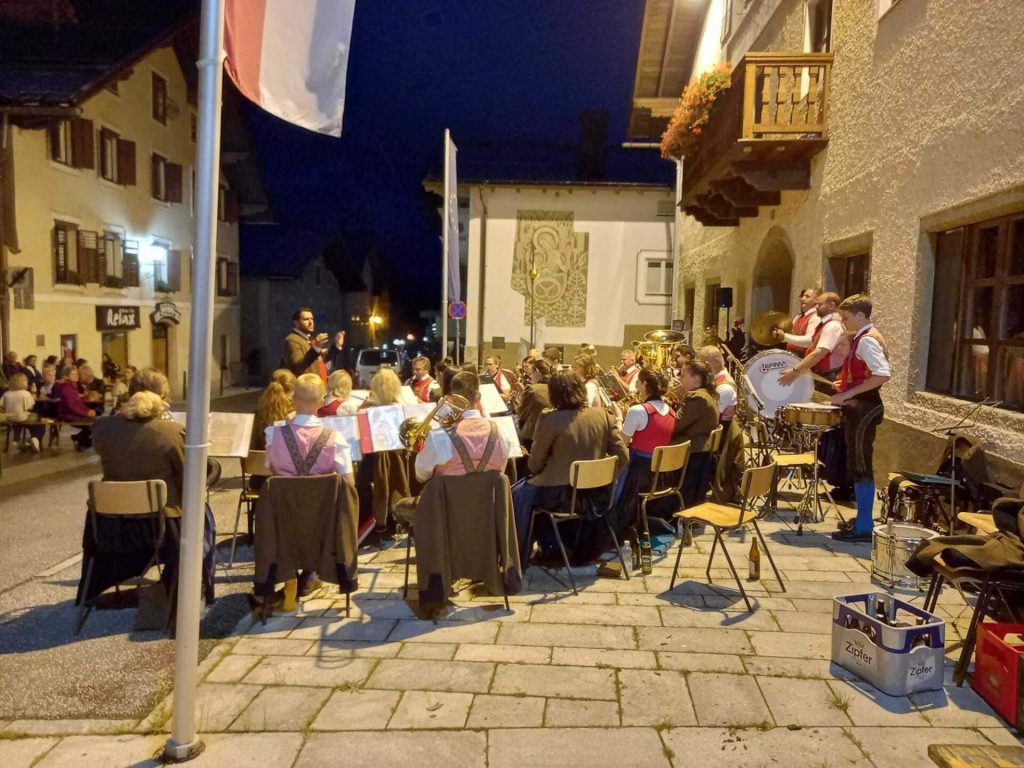 Trachtenmusikkapelle spielt im Freien, Publikum genießt die Abendkonzerte in Taxenbach.